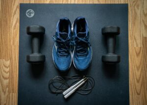 tennis shoes, weights and a jump rope sitting on a Manduka yoga mat, illustrating the importance of a culture of health and fitness in the workplace