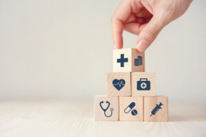 Hand stacking blocks with healthcare images stamped on the face.