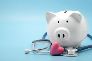 White piggy bank surrounded by a stethoscope on a light blue background