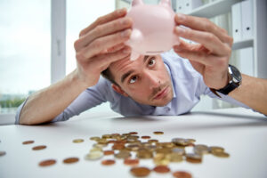 Man shaking coins out of pink piggy bank