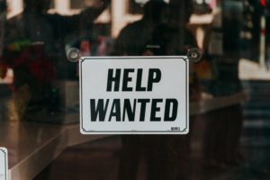 A help wanted sign in a window, illustrating a post about the labor shortage