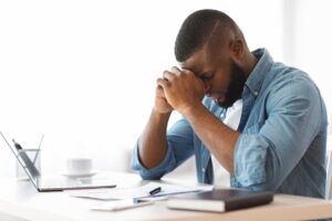 Stressed employee with his head in his hands at his desk