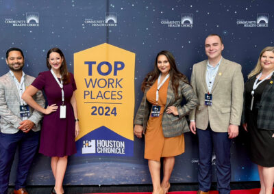 Five BCH team members in front of a Houston Chronicle Top Workplaces banner