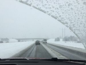 View through a windshield of a highway surrounded by snow, illustrating an article about winter storm safety
